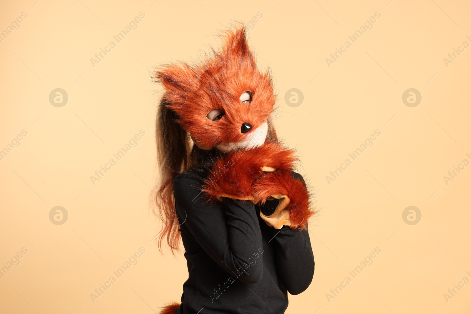 Photo of Quadrobics. Girl wearing fox mask and gloves on beige background