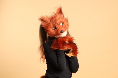 Photo of Quadrobics. Girl wearing fox mask and gloves on beige background