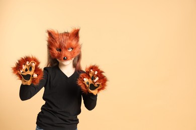 Photo of Quadrobics. Girl wearing fox mask and gloves on beige background, space for text