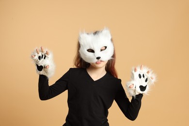 Photo of Quadrobics. Girl wearing cat mask and gloves on beige background