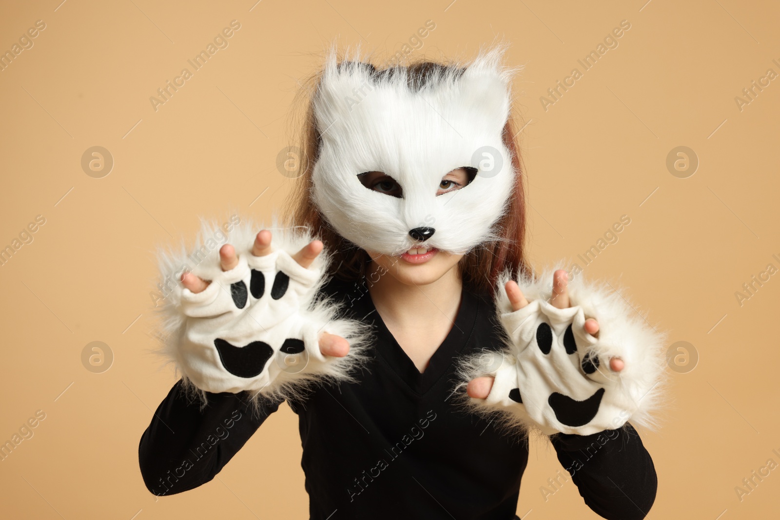 Photo of Quadrobics. Girl wearing cat mask and gloves on beige background