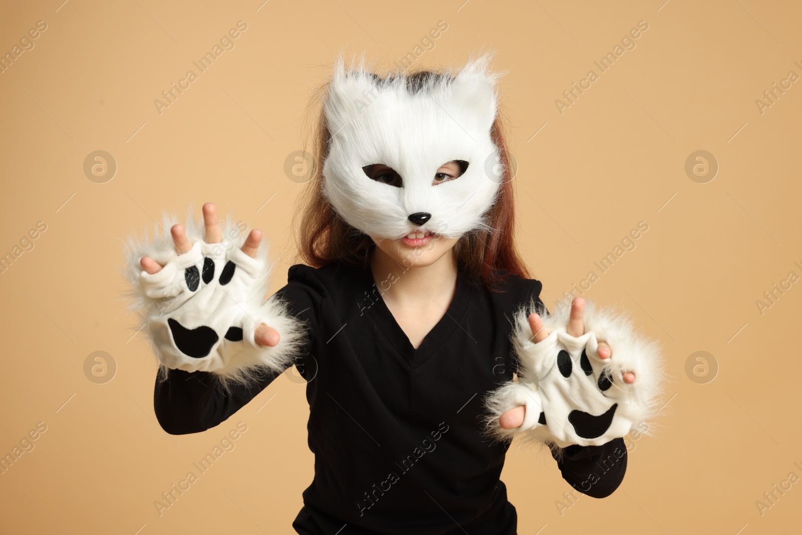 Photo of Quadrobics. Girl wearing cat mask and gloves on beige background