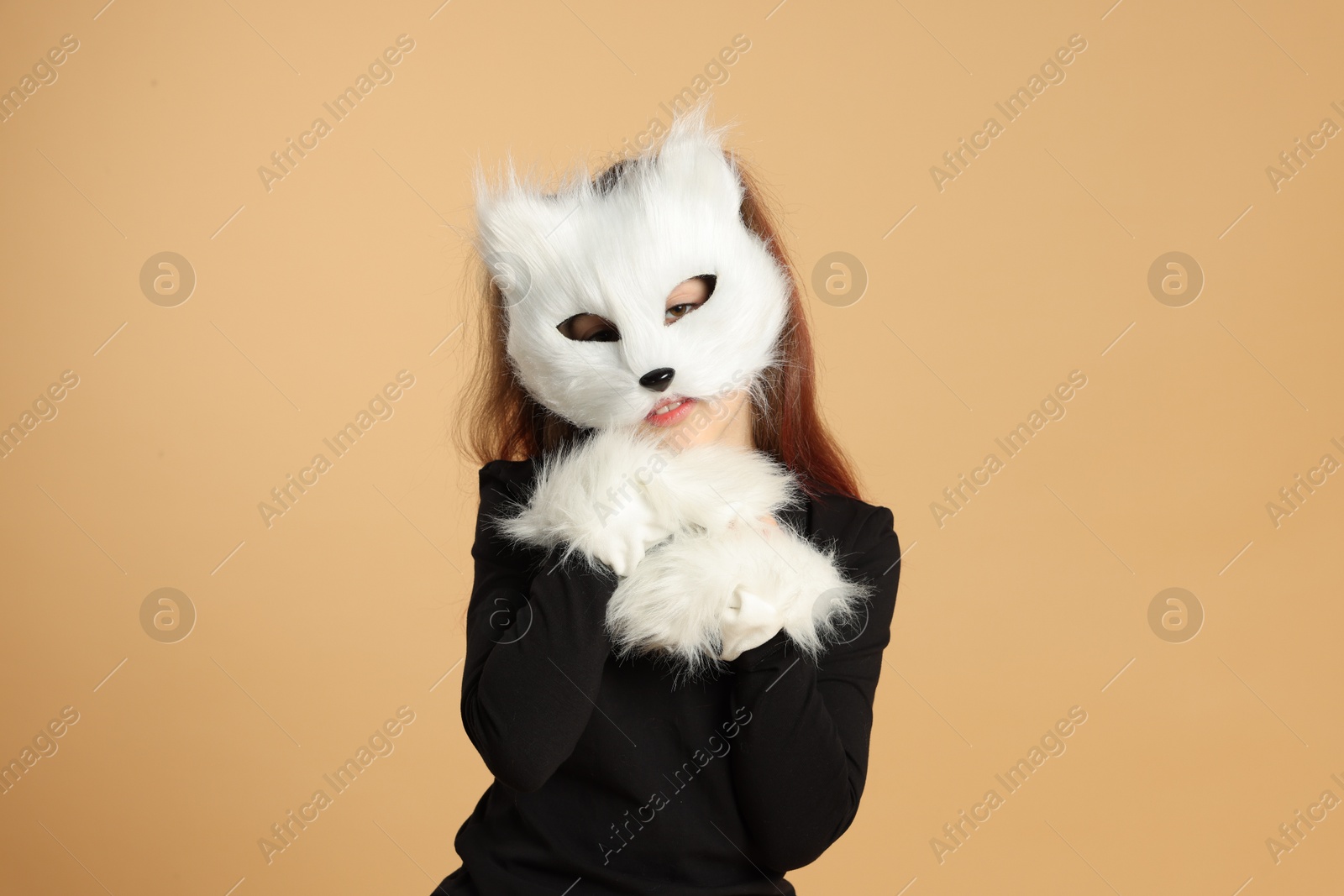 Photo of Quadrobics. Girl wearing cat mask and gloves on beige background