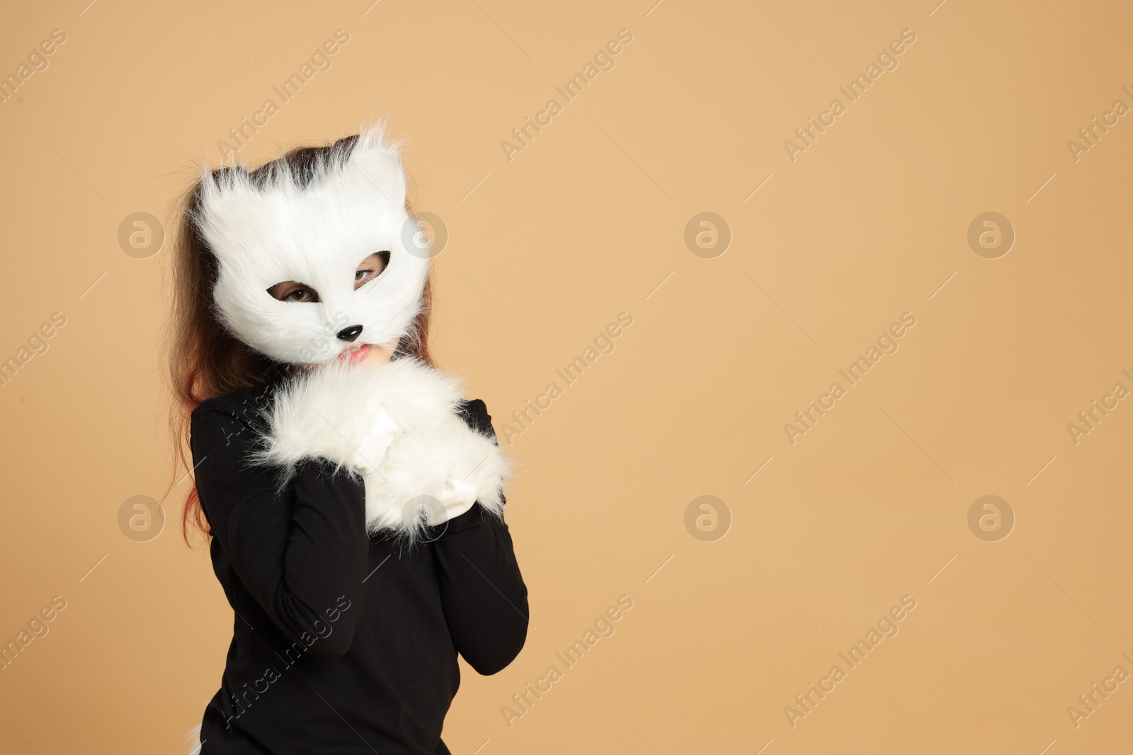 Photo of Quadrobics. Girl wearing cat mask and gloves on beige background, space for text