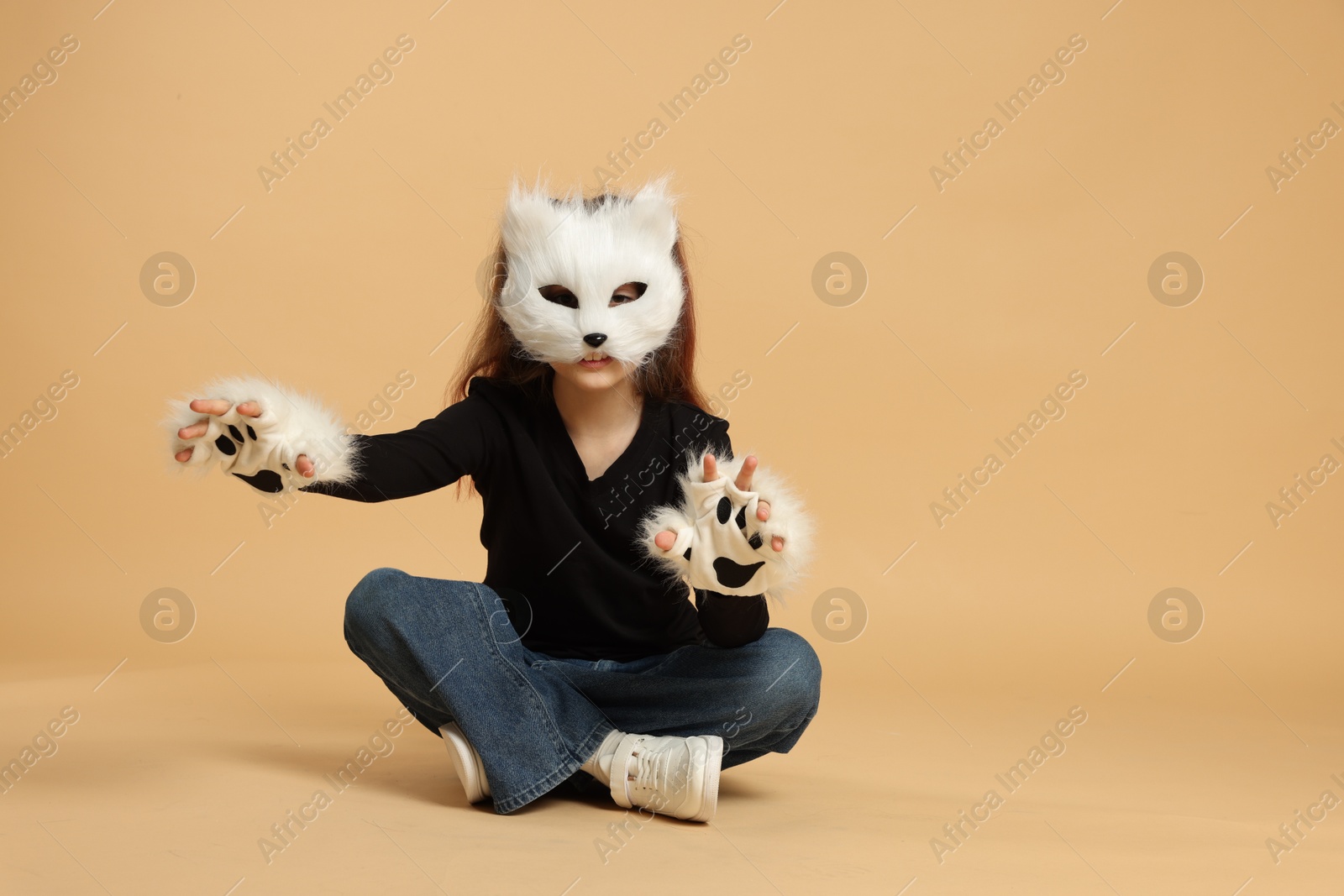 Photo of Quadrobics. Girl wearing cat mask and gloves on beige background, space for text