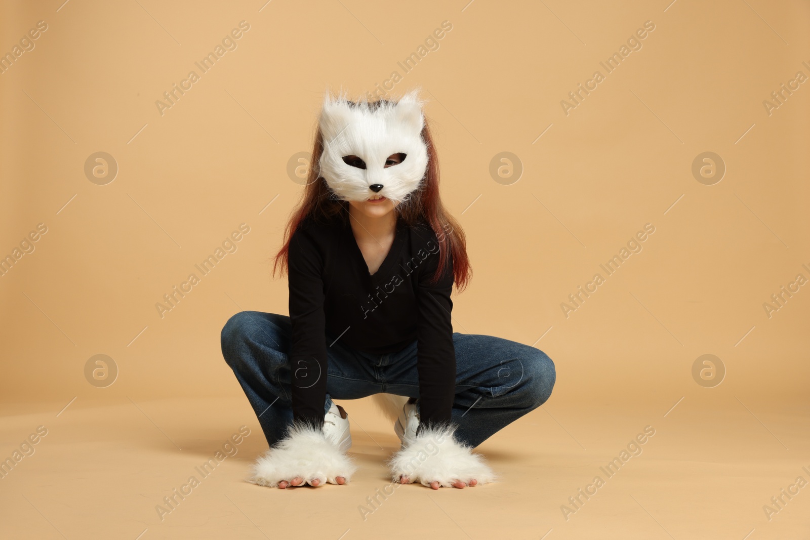 Photo of Quadrobics. Girl wearing cat mask and gloves on beige background