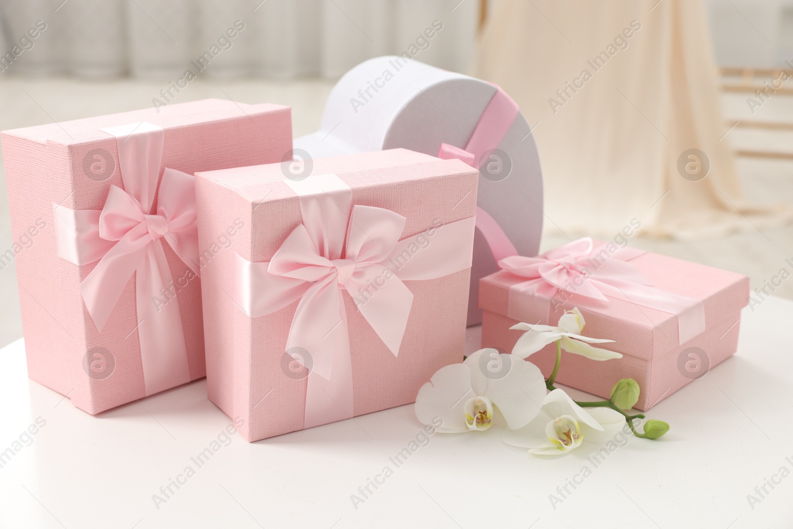 Photo of Gift boxes for wedding day and orchid flowers on white table indoors, closeup