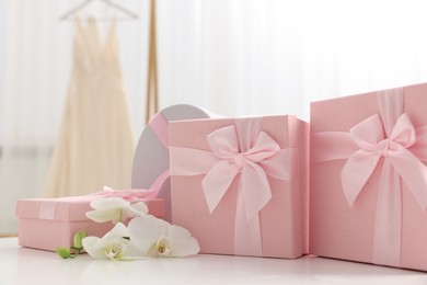 Photo of Gift boxes for wedding day and orchid flowers on white table indoors, closeup