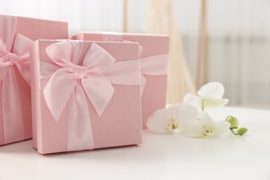 Photo of Gift boxes for wedding day and orchid flowers on white table indoors, closeup. Space for text