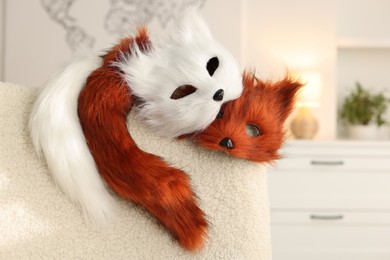 Photo of Quadrobics. Fox and cat masks with tails on armchair indoors