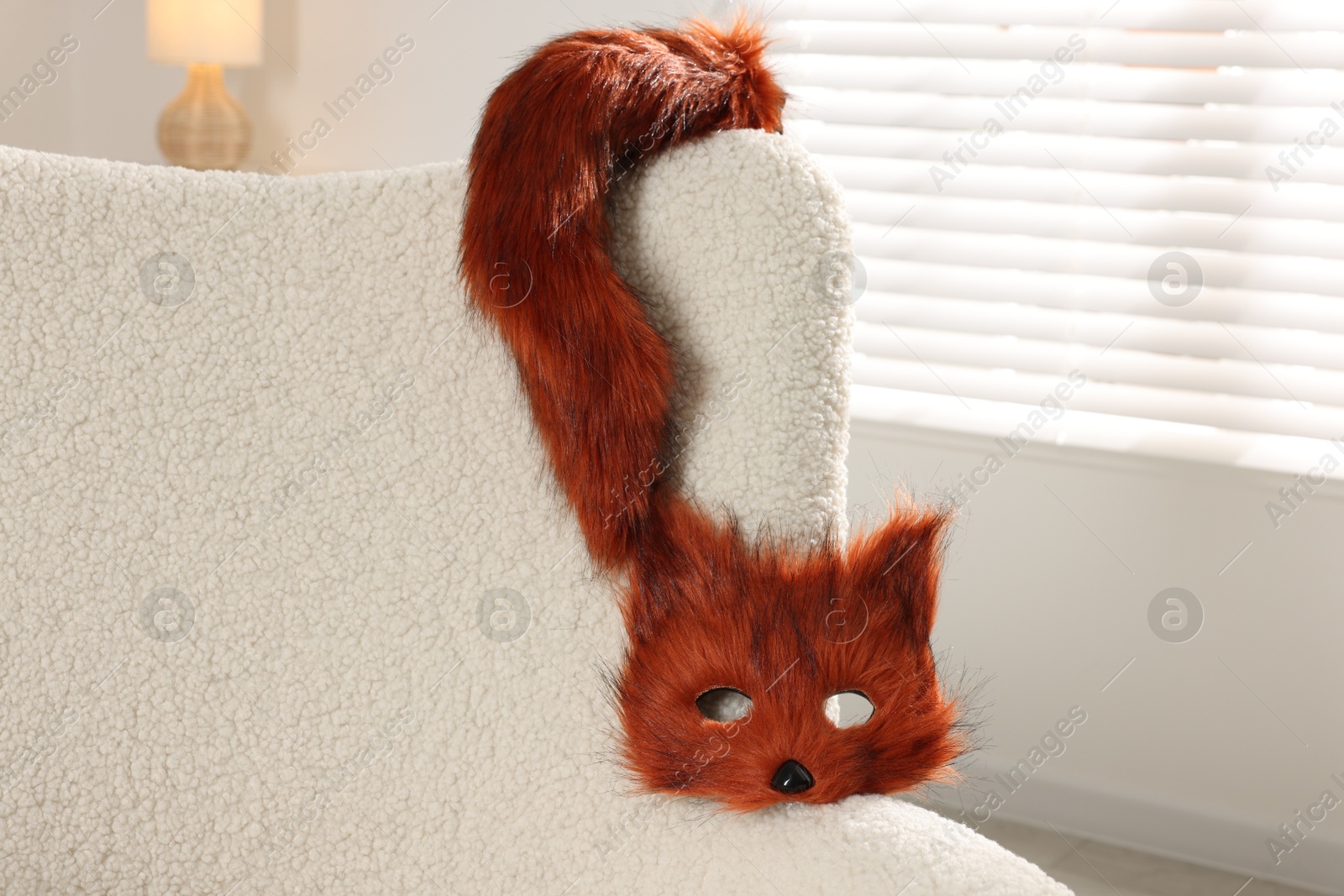 Photo of Quadrobics. Fox mask and tail on armchair indoors, space for text