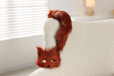 Photo of Quadrobics. Fox mask and tail on armchair indoors