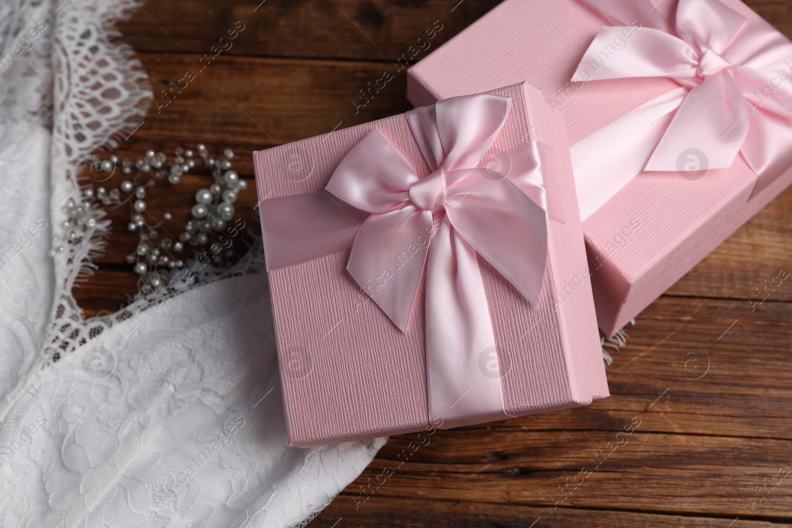 Photo of Gift boxes for wedding day and bridal dress on wooden background, flat lay