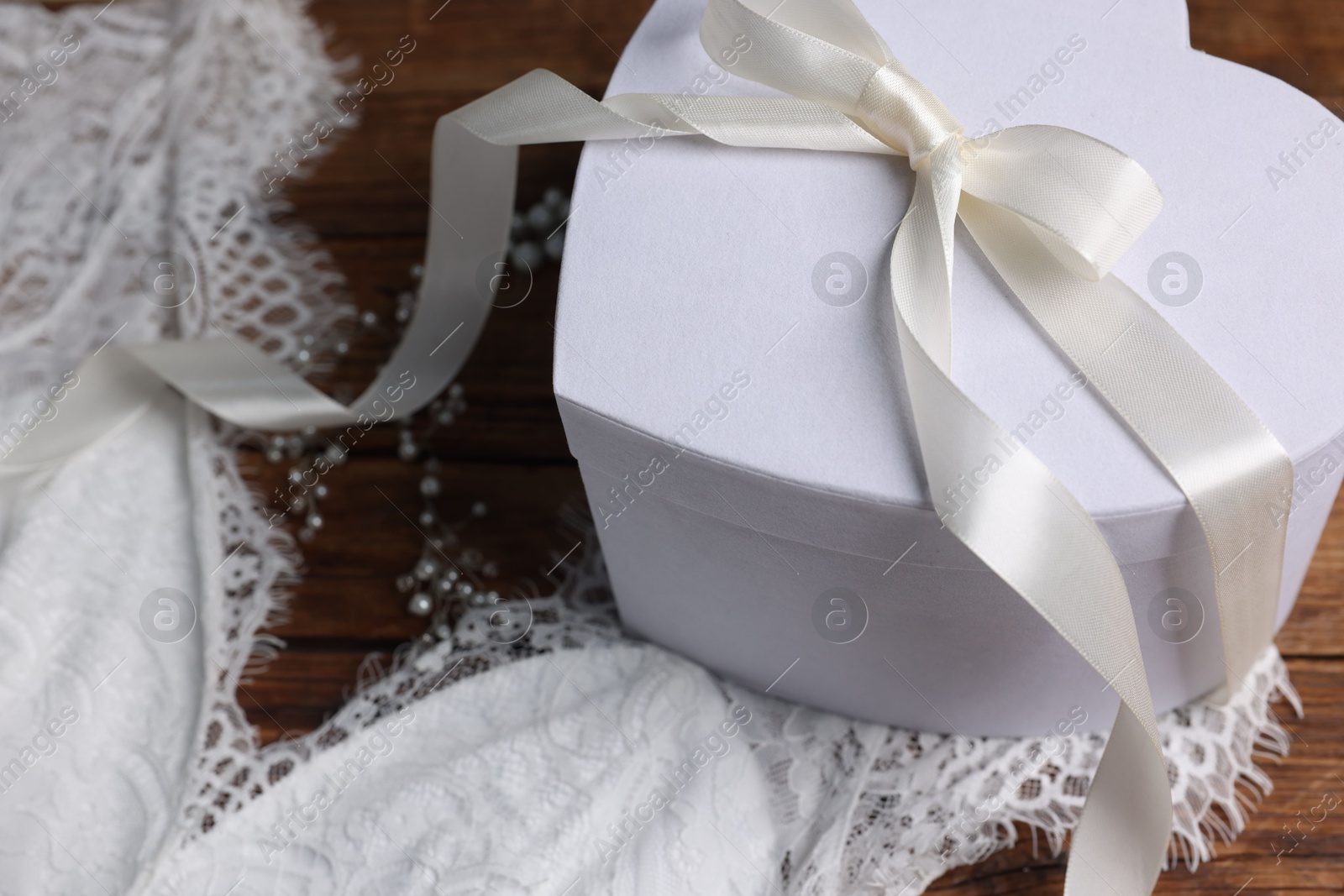 Photo of Gift box for wedding day and bridal dress on brown surface, closeup