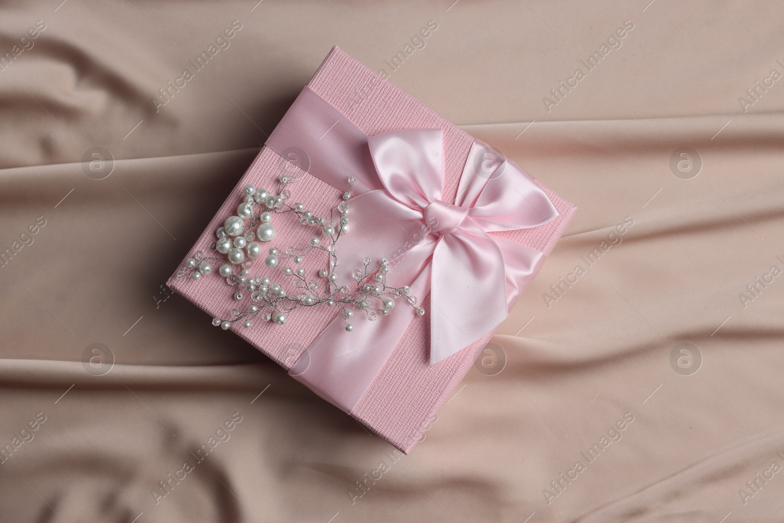 Photo of Gift box for wedding day and hair accessory on beige fabric, top view