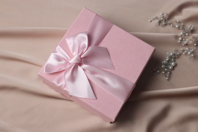 Photo of Gift box for wedding day and hair accessory on beige fabric, flat lay