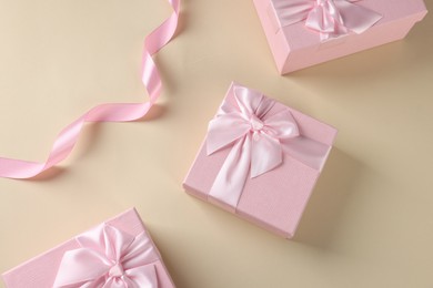 Photo of Gift boxes for wedding day and ribbon on beige background, flat lay