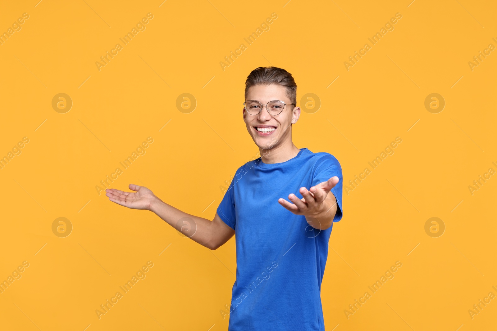 Photo of Happy man welcoming friends or guests on orange background