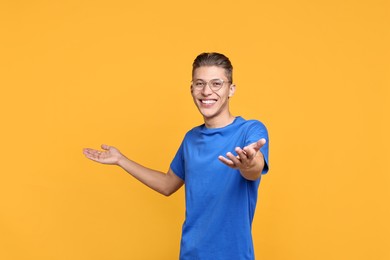 Photo of Happy man welcoming friends or guests on orange background