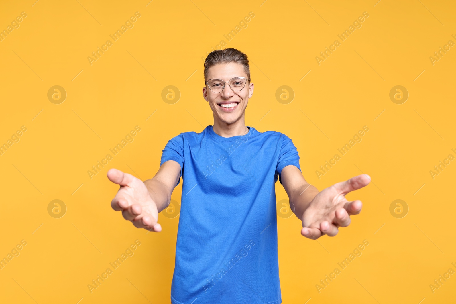 Photo of Happy man welcoming friends or guests on orange background