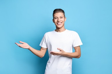 Photo of Happy man welcoming friends or guests on light blue background