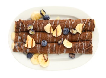 Photo of Delicious chocolate crepes with banana and blueberries isolated on white, top view