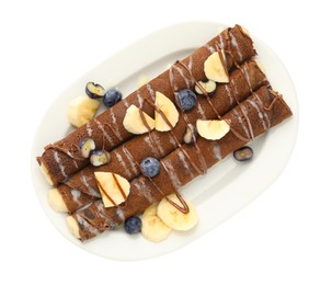 Photo of Delicious chocolate crepes with banana and blueberries isolated on white, top view