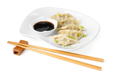 Photo of Tasty gyoza (dumplings), soy sauce and chopsticks isolated on white