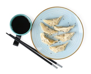 Photo of Tasty gyoza (dumplings), soy sauce and chopsticks isolated on white, top view