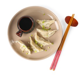 Photo of Tasty gyoza (dumplings), soy sauce and chopsticks isolated on white, top view