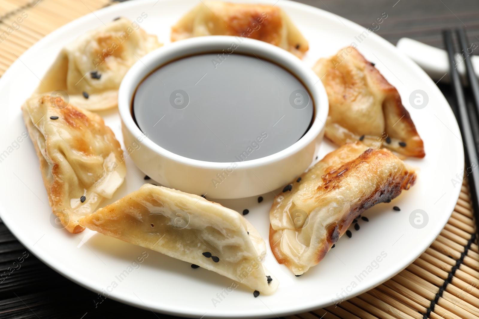 Photo of Delicious fried gyoza dumplings with sesame seeds served on table, closeup