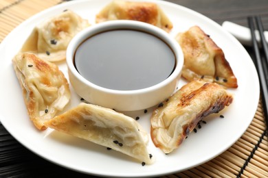 Photo of Delicious fried gyoza dumplings with sesame seeds served on table, closeup