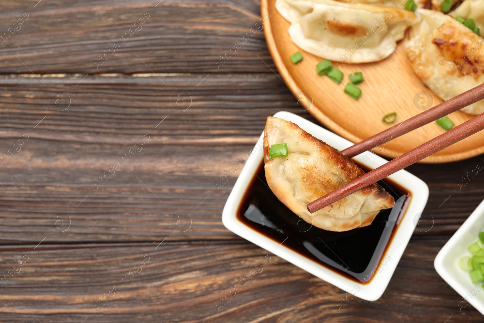 Photo of Eating fried gyoza dumplings at wooden table, top view. Space for text