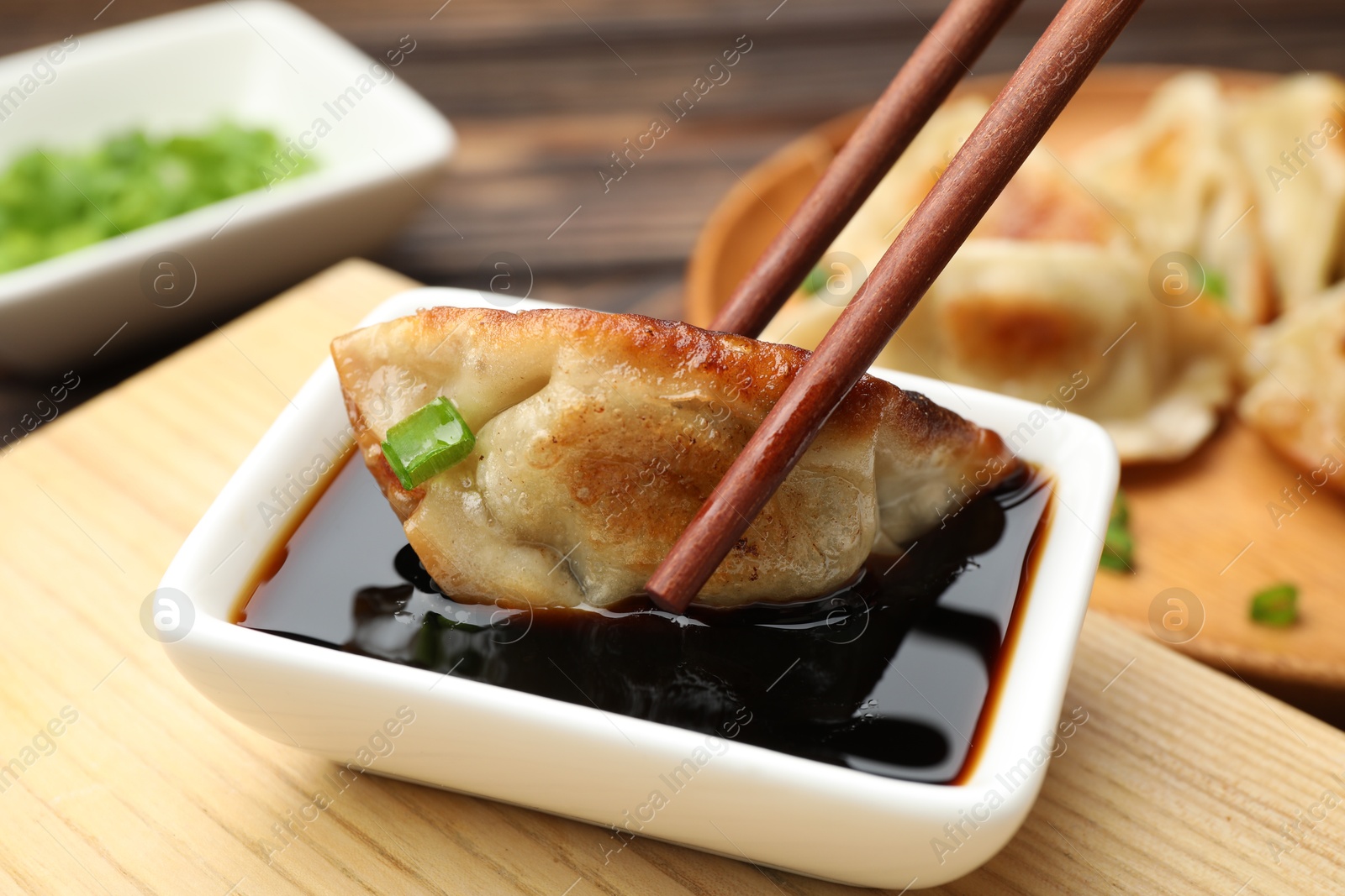 Photo of Eating fried gyoza dumplings at wooden table, closeup