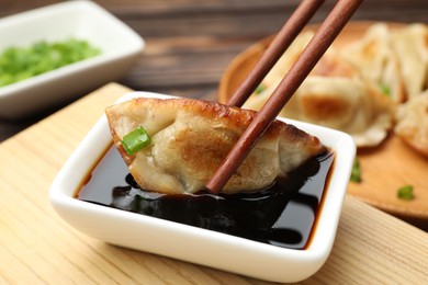 Photo of Eating fried gyoza dumplings at wooden table, closeup