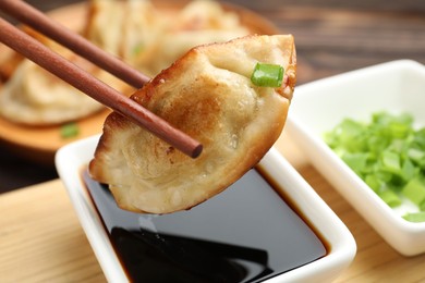 Photo of Eating fried gyoza dumplings at wooden table, closeup