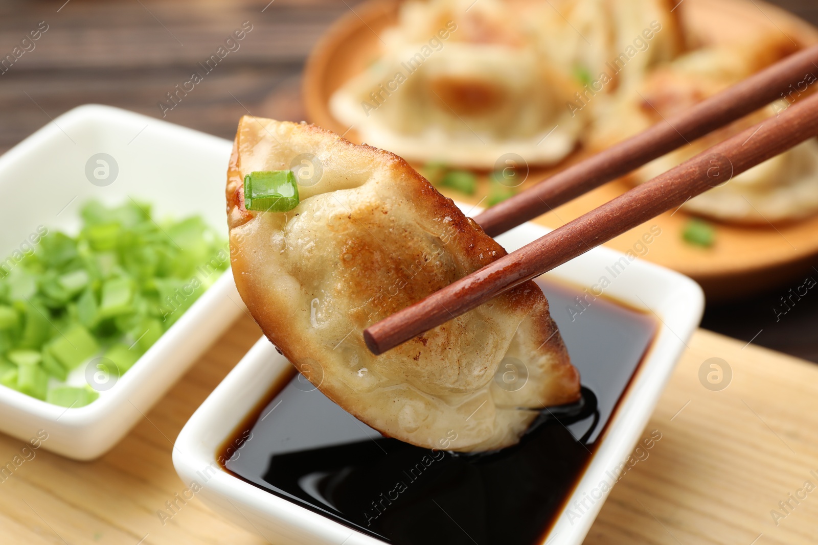 Photo of Eating fried gyoza dumplings at wooden table, closeup