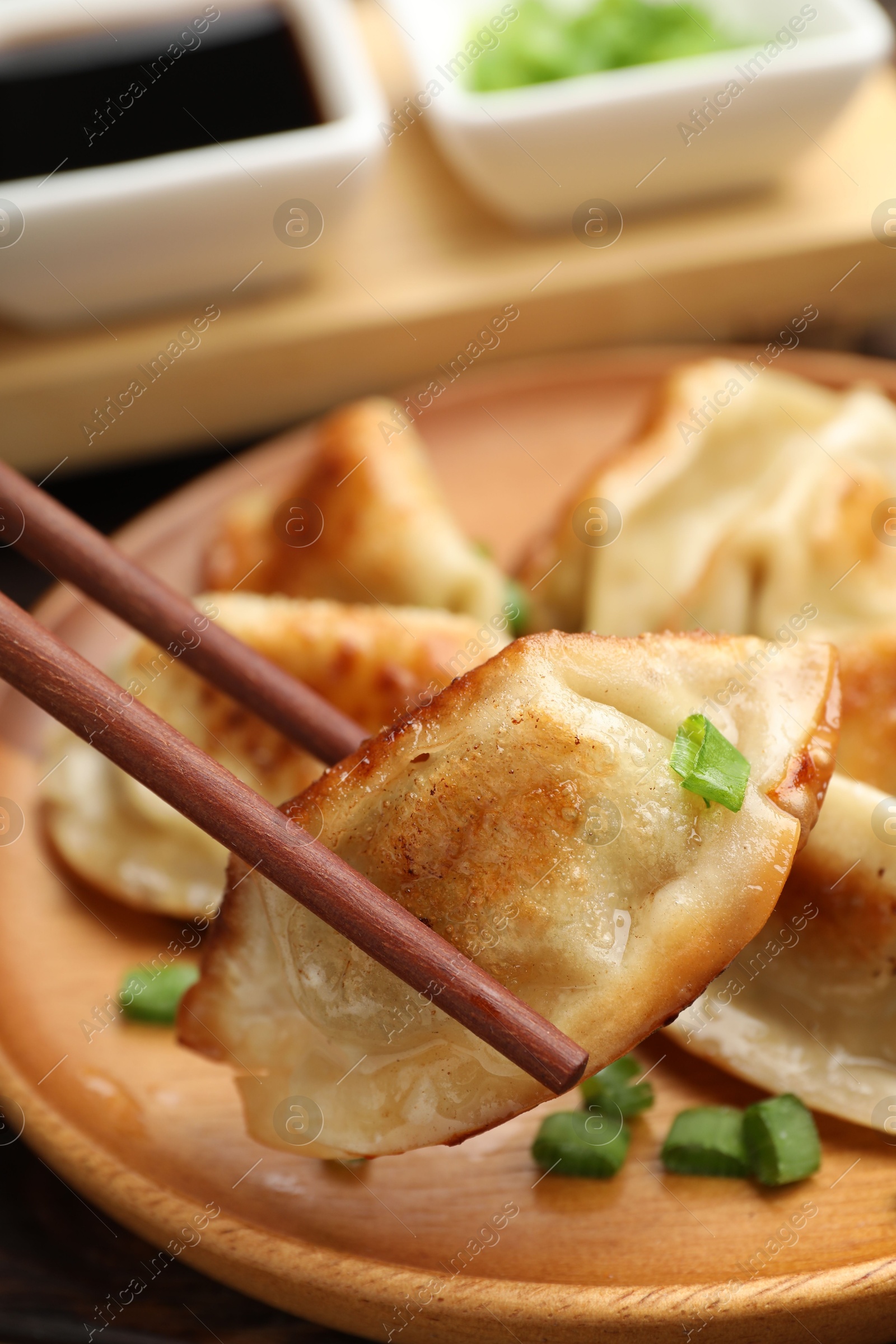 Photo of Eating fried gyoza dumplings at wooden table, closeup