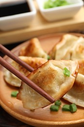 Eating fried gyoza dumplings at wooden table, closeup