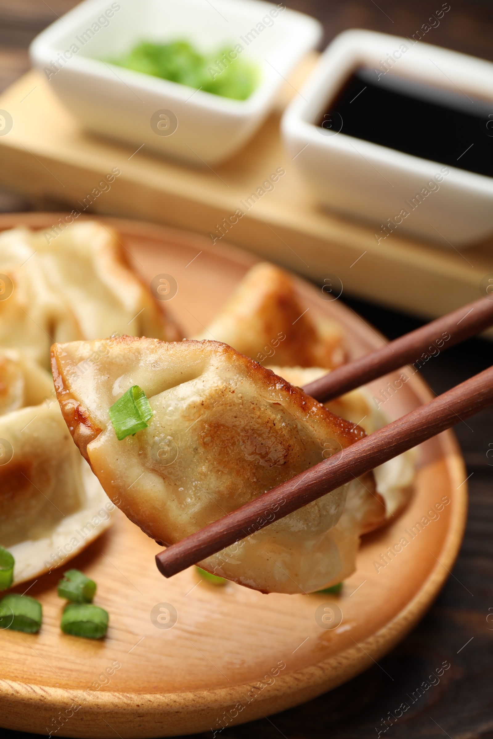 Photo of Eating fried gyoza dumplings at wooden table, closeup