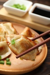 Photo of Eating fried gyoza dumplings at wooden table, closeup