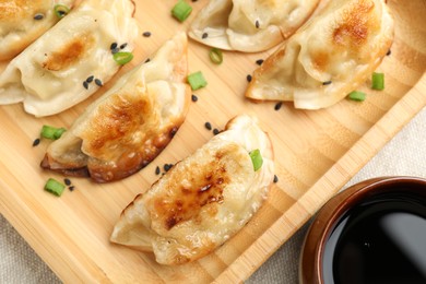 Photo of Delicious fried gyoza dumplings with green onions and soy sauce on table, top view