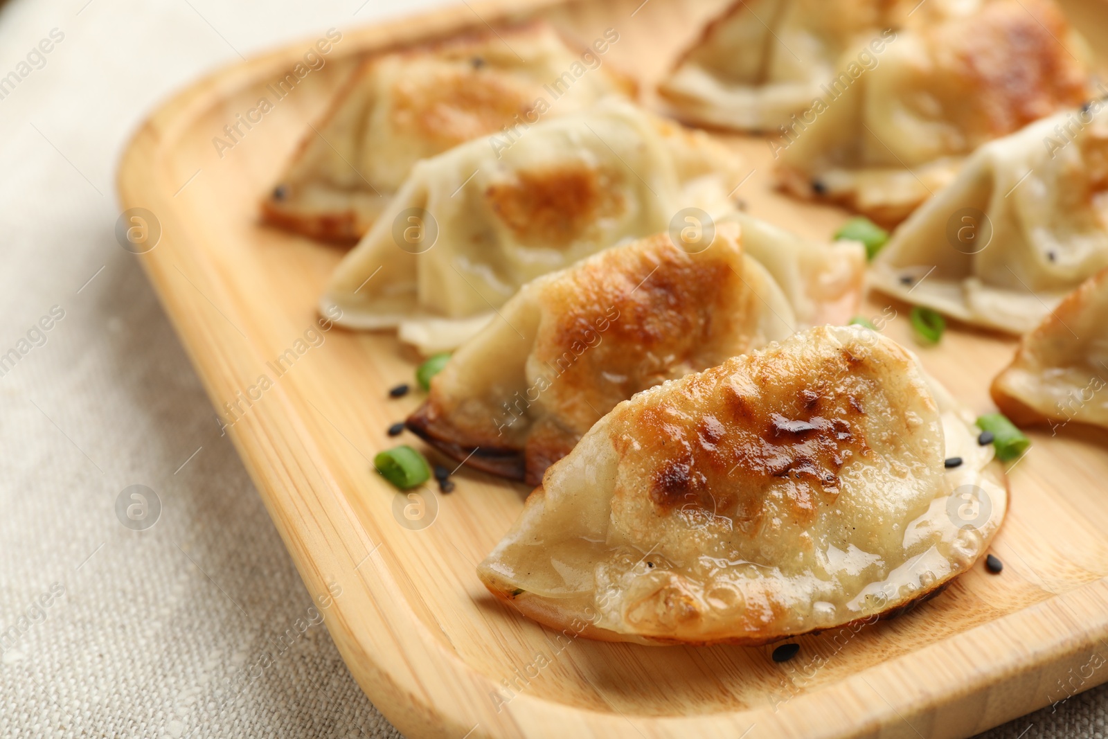 Photo of Delicious fried gyoza dumplings with green onions on table, closeup