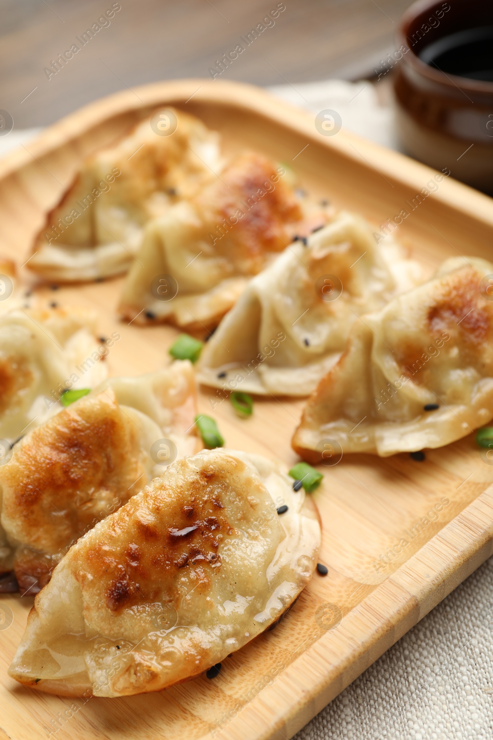 Photo of Delicious fried gyoza dumplings with green onions on table, closeup