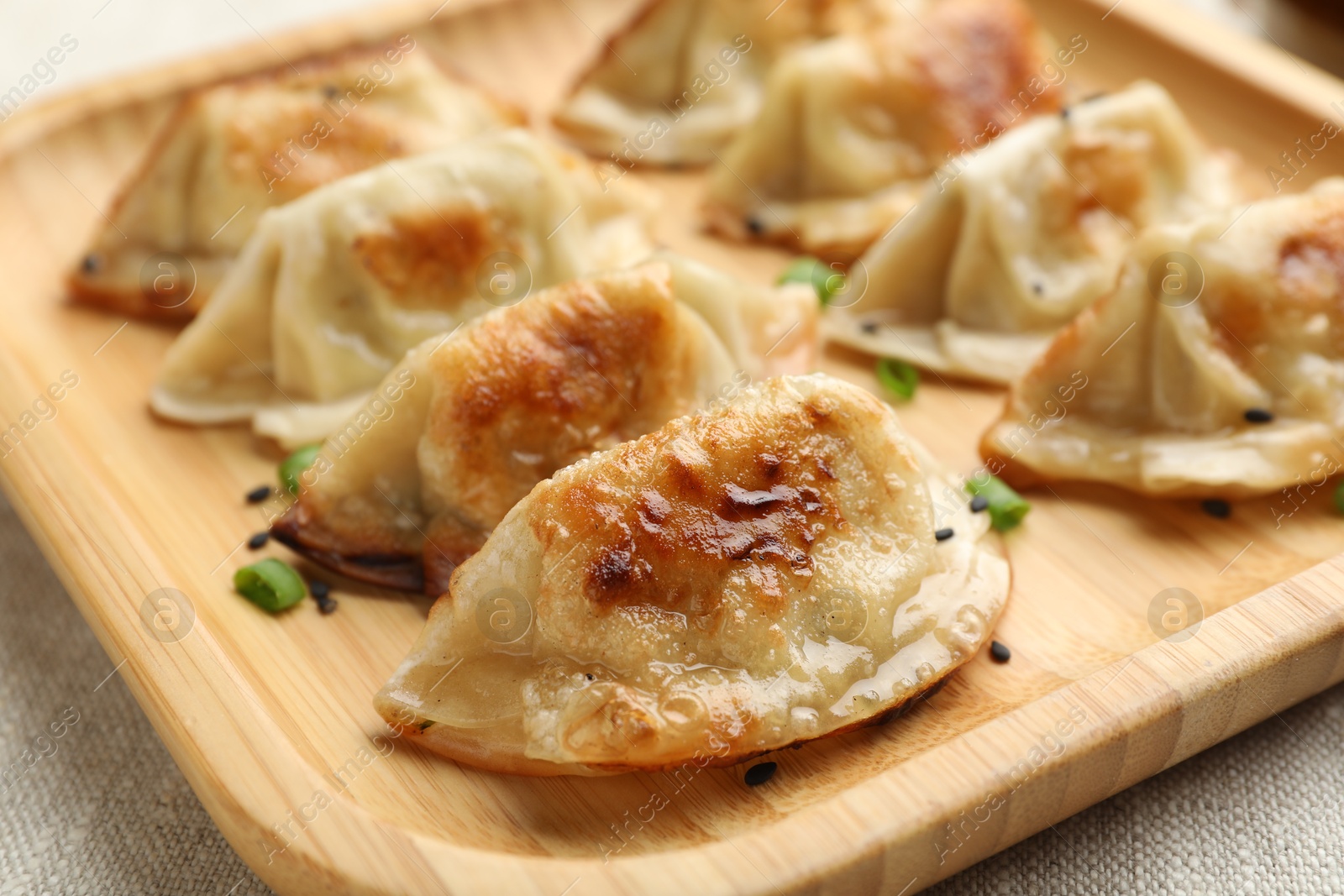 Photo of Delicious fried gyoza dumplings with green onions on table, closeup