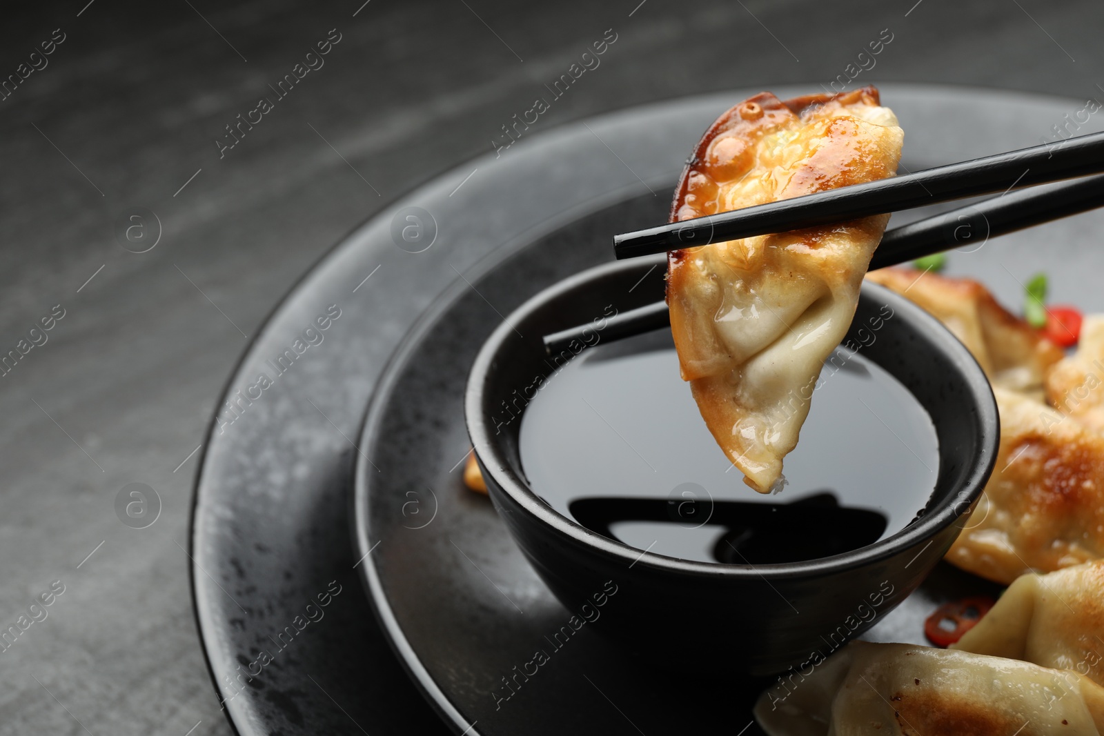 Photo of Eating fried gyoza dumplings at black table, closeup. Space for text