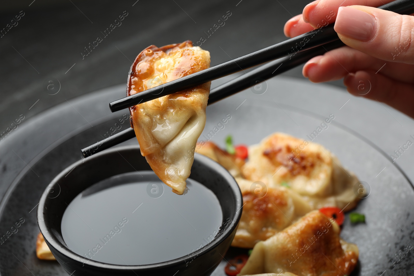 Photo of Woman eating fried gyoza dumplings at black table, closeup