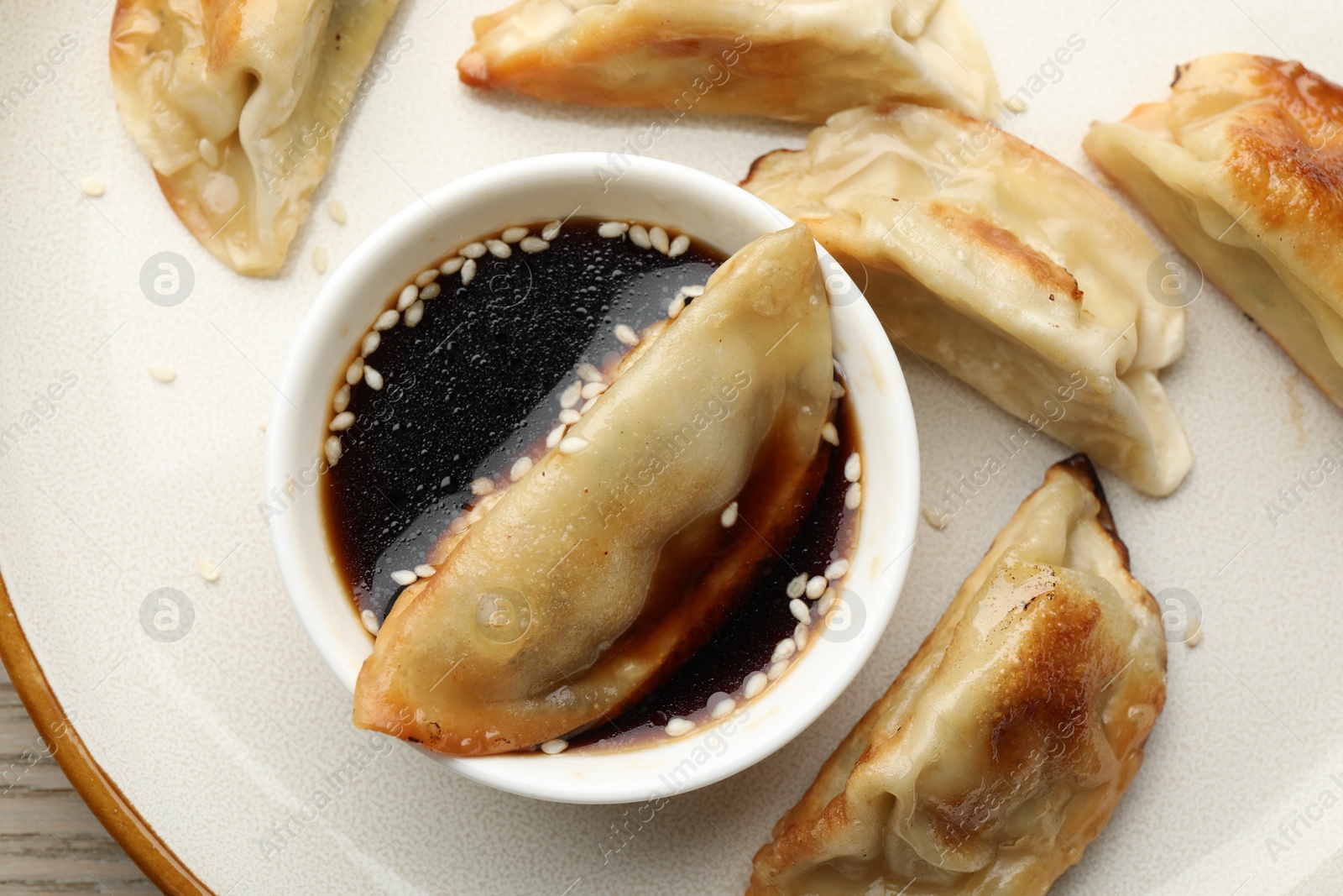 Photo of Fried gyoza dumplings with soy sauce on table, top view