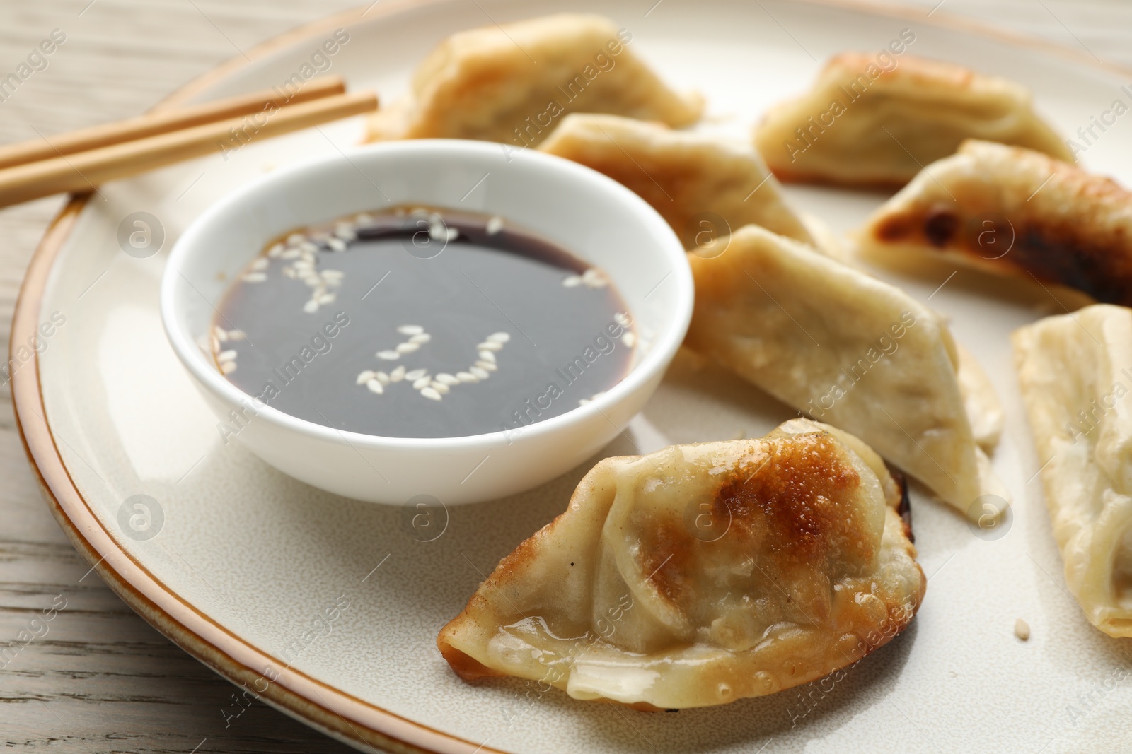 Photo of Delicious fried gyoza dumplings served on wooden table, closeup