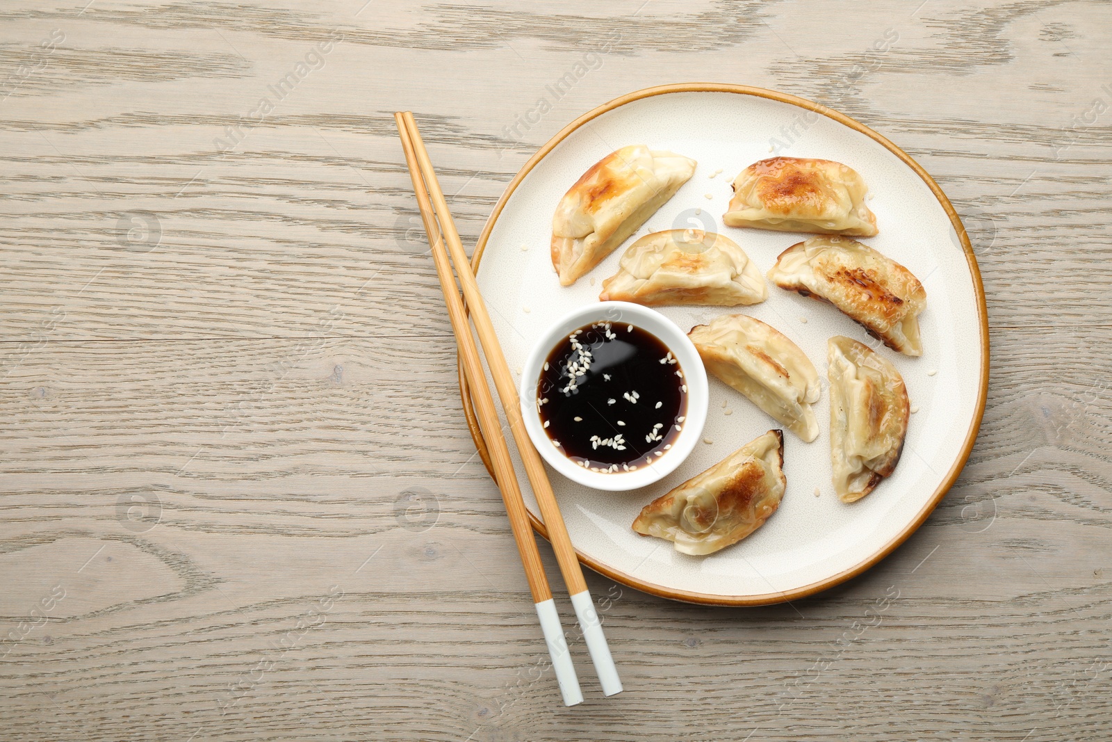 Photo of Delicious fried gyoza dumplings served on wooden table, top view. Space for text